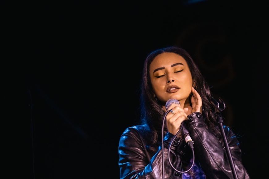 Leah Weller holding a microphone singing with her eyes closed