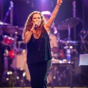 Sandra Mihanovich performing live on stage, singing passionately with microphone, at a concert ahead of her 2025 show at The Cavern Club in Liverpool.